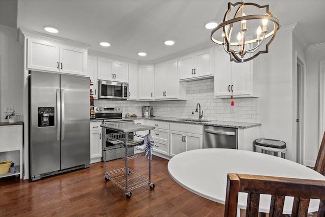 kitchen featuring stainless steel appliances, dark wood-type flooring, sink, a notable chandelier, and hanging light fixtures