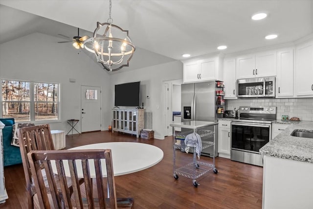 kitchen with light stone countertops, hanging light fixtures, dark hardwood / wood-style flooring, white cabinets, and appliances with stainless steel finishes