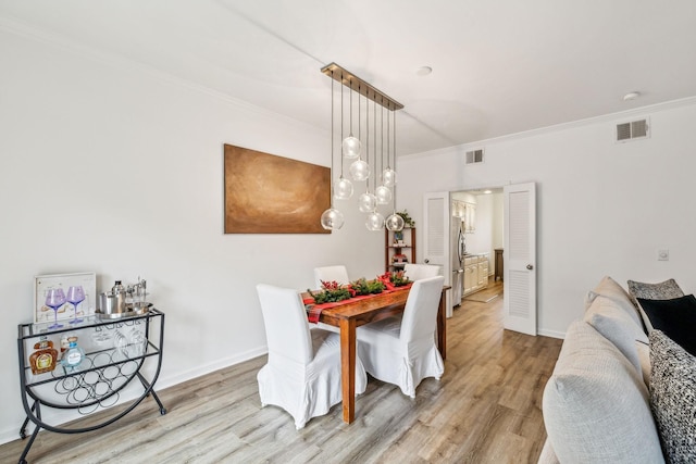 dining room featuring light hardwood / wood-style flooring and ornamental molding