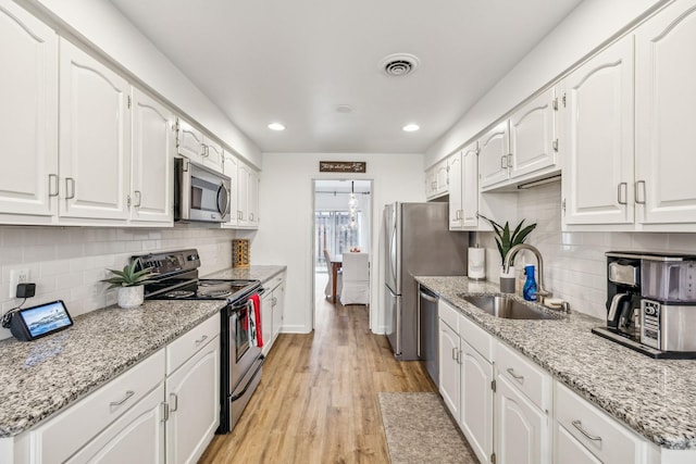 kitchen with white cabinetry, sink, stainless steel appliances, and light hardwood / wood-style floors