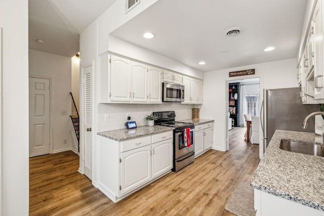 kitchen with white cabinets, light stone counters, and appliances with stainless steel finishes