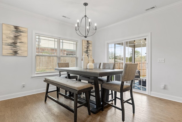 dining room featuring a chandelier, hardwood / wood-style floors, a wealth of natural light, and ornamental molding