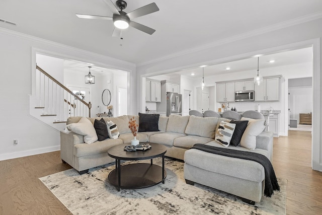 living room featuring light hardwood / wood-style floors, ceiling fan with notable chandelier, and ornamental molding