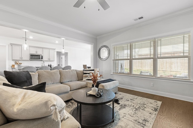 living room featuring dark hardwood / wood-style floors, ceiling fan, and crown molding