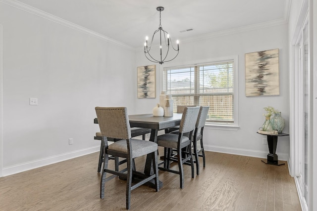 dining space with ornamental molding, wood-type flooring, and an inviting chandelier