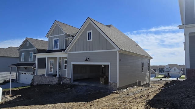 view of front facade with board and batten siding, roof with shingles, and an attached garage