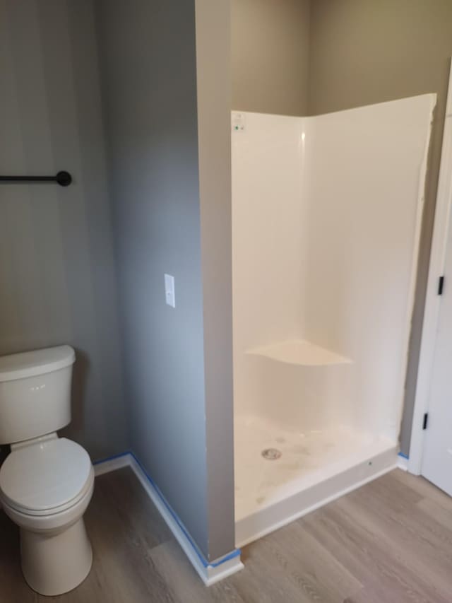 bathroom featuring hardwood / wood-style floors, toilet, and walk in shower