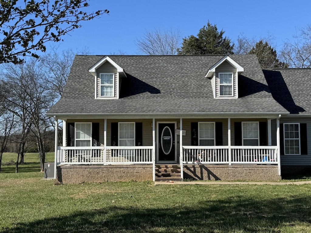 cape cod home featuring a porch and a front lawn