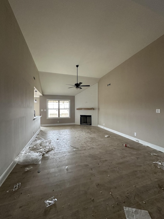 unfurnished living room with a ceiling fan, a fireplace, baseboards, and high vaulted ceiling