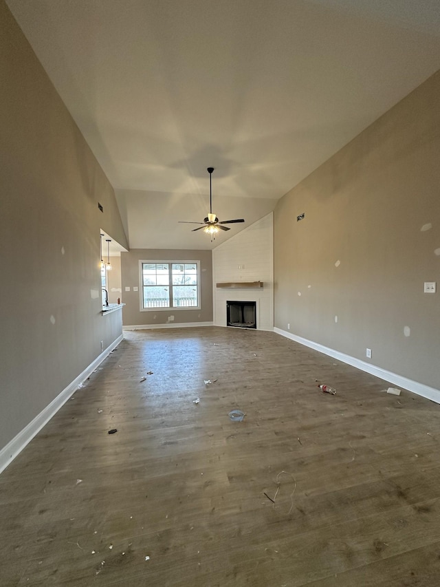 unfurnished living room featuring dark wood-style floors, baseboards, high vaulted ceiling, a fireplace, and ceiling fan