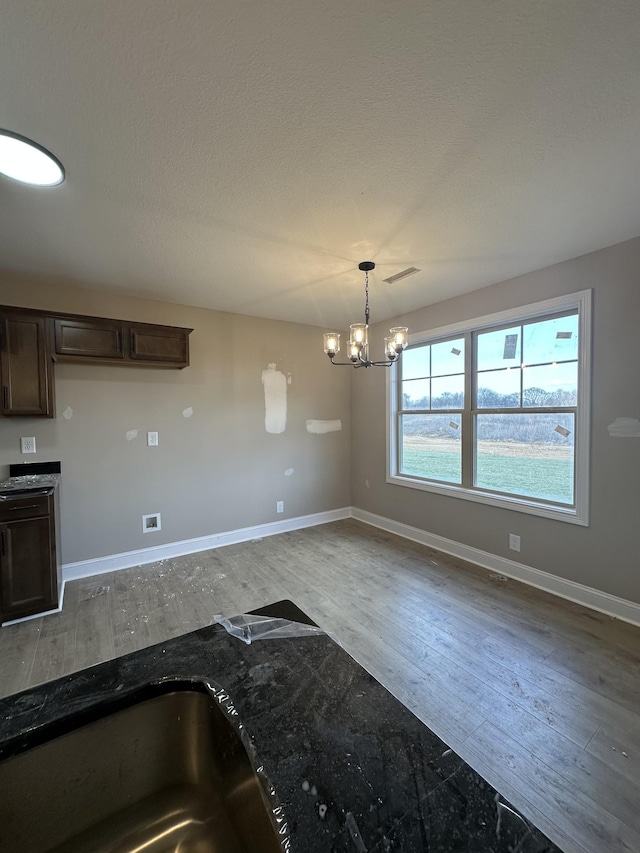 kitchen featuring visible vents, baseboards, dark brown cabinets, and wood finished floors