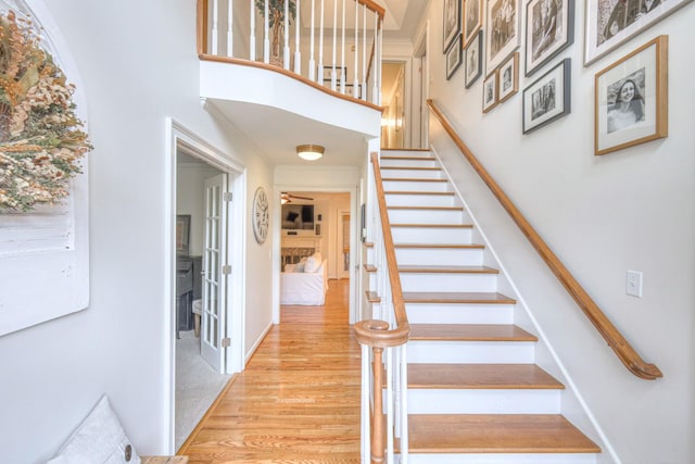 stairs featuring wood-type flooring and ornamental molding