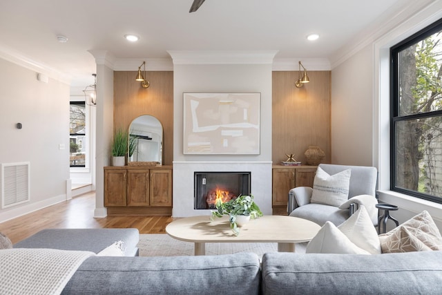 living room featuring ornamental molding, a healthy amount of sunlight, and light wood-type flooring