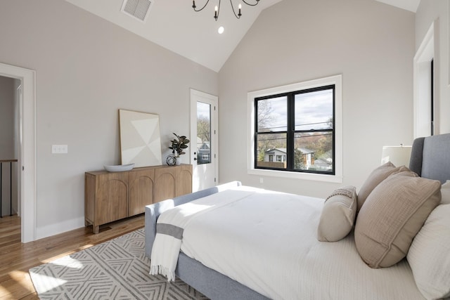 bedroom featuring vaulted ceiling, an inviting chandelier, and light hardwood / wood-style flooring