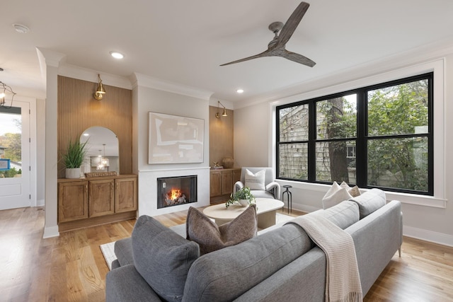 living room featuring ornamental molding, ceiling fan, and light hardwood / wood-style floors