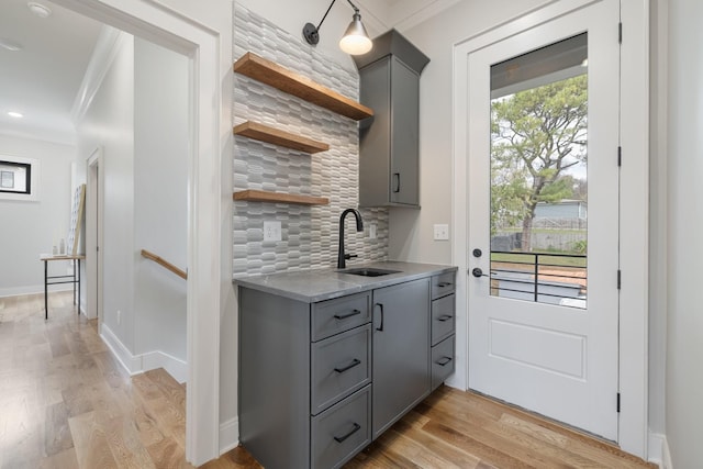 interior space featuring gray cabinets, crown molding, sink, and decorative backsplash