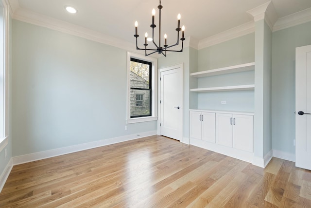 unfurnished dining area featuring built in shelves, ornamental molding, an inviting chandelier, and light hardwood / wood-style floors