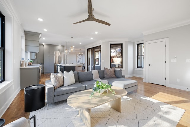 living room featuring ornamental molding, sink, ceiling fan, and light hardwood / wood-style floors