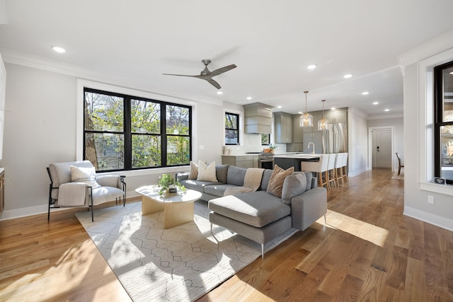 living room featuring light hardwood / wood-style flooring, ornamental molding, and ceiling fan