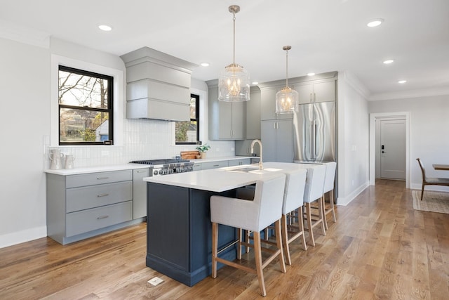 kitchen featuring sink, gray cabinetry, an island with sink, custom range hood, and light hardwood / wood-style floors