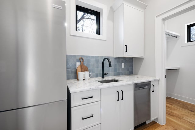 kitchen with sink, light stone countertops, white cabinets, and appliances with stainless steel finishes