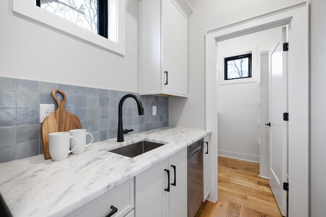 kitchen featuring white cabinetry, dishwasher, sink, and light stone counters