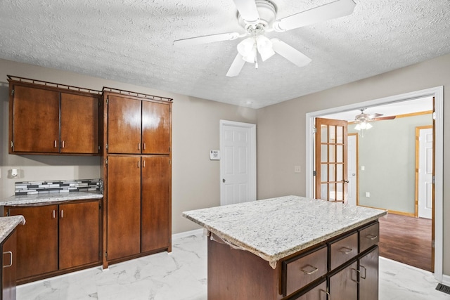 kitchen with french doors, a textured ceiling, a center island, and ceiling fan