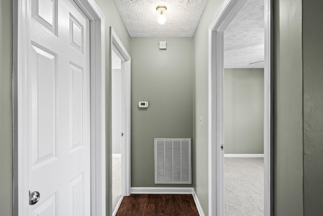 corridor featuring a textured ceiling and dark wood-type flooring