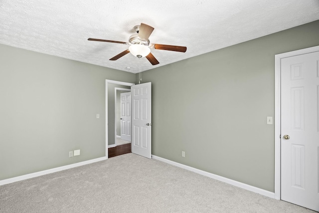 unfurnished bedroom with ceiling fan, light carpet, and a textured ceiling