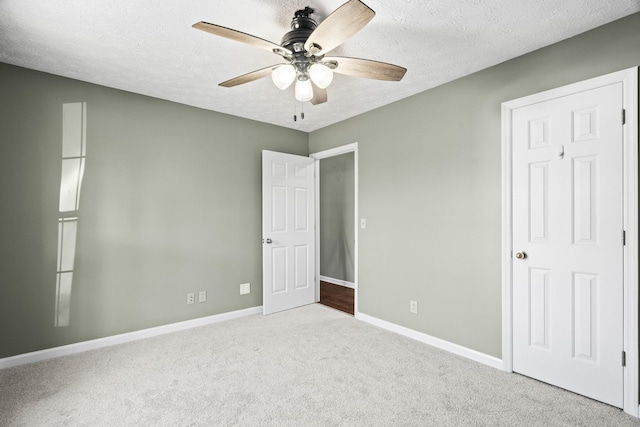 unfurnished bedroom with a textured ceiling, light colored carpet, and ceiling fan