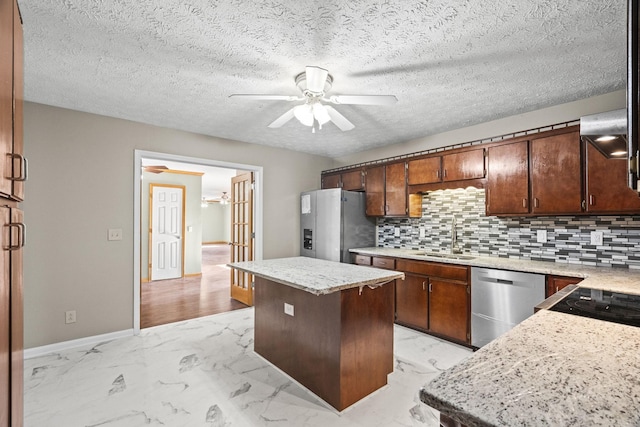 kitchen with ceiling fan, sink, backsplash, a kitchen island, and appliances with stainless steel finishes