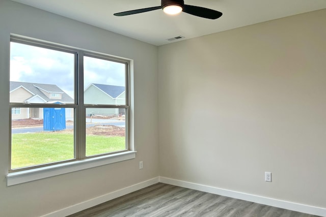 empty room with hardwood / wood-style floors, a wealth of natural light, and ceiling fan