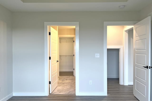 unfurnished bedroom featuring hardwood / wood-style floors, a walk in closet, and a closet