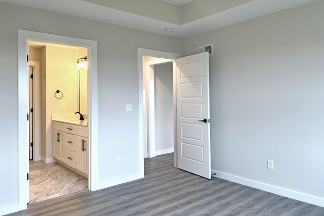 unfurnished bedroom with light hardwood / wood-style floors, ensuite bath, and sink