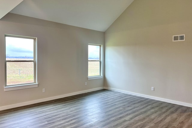 spare room with a wealth of natural light, dark hardwood / wood-style flooring, and vaulted ceiling