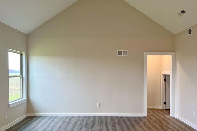 spare room with hardwood / wood-style floors and high vaulted ceiling