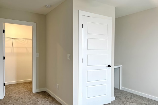 unfurnished bedroom with a walk in closet, a closet, and carpet