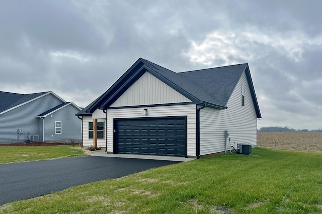 view of front of house featuring central air condition unit, a front yard, and a garage