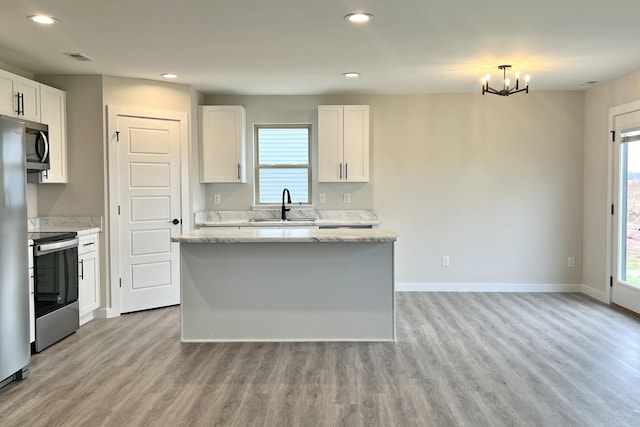 kitchen with light wood-type flooring, stainless steel appliances, white cabinetry, and sink