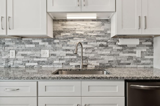 kitchen with light stone countertops, sink, stainless steel dishwasher, backsplash, and white cabinets