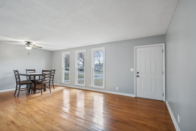 dining space with ceiling fan, light hardwood / wood-style floors, and a textured ceiling