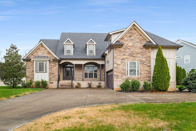 view of front of property featuring a porch, a garage, and a front yard