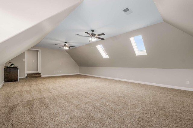 bonus room with light colored carpet, lofted ceiling with skylight, and ceiling fan