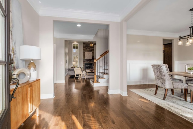 entryway with a stone fireplace, dark hardwood / wood-style flooring, and ornamental molding