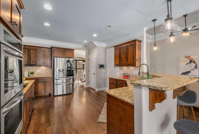 kitchen featuring light stone countertops, sink, dark hardwood / wood-style floors, decorative light fixtures, and appliances with stainless steel finishes