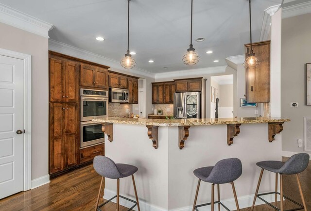 kitchen featuring a kitchen breakfast bar, light stone counters, appliances with stainless steel finishes, dark hardwood / wood-style flooring, and kitchen peninsula