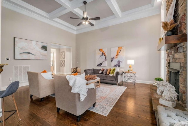 living room with coffered ceiling, a stone fireplace, ceiling fan, beamed ceiling, and dark hardwood / wood-style flooring