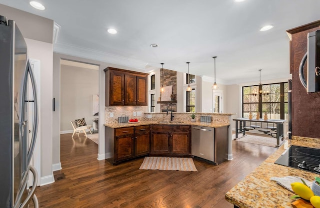 kitchen featuring light stone countertops, pendant lighting, stainless steel appliances, and sink