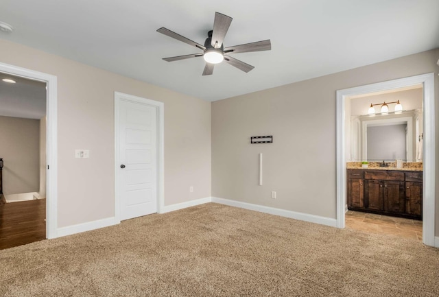 unfurnished bedroom with light carpet, ensuite bath, and ceiling fan