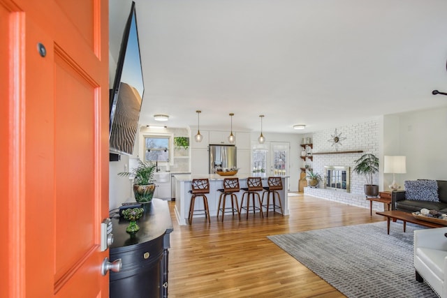 living room featuring a brick fireplace and light wood-type flooring